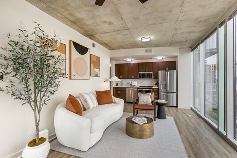 a living room with a white couch and coffee table and a kitchen with stainless steel appliances